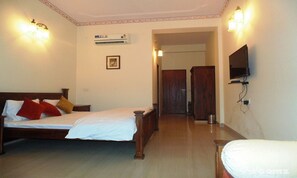 Classic hotel room with a wooden bed, flat-screen TV, and air conditioning unit.