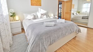 A modern bedroom with a large bed, bedside tables, a mirror, and a decorative wall piece. - Artemis - Markovac Višnjan, cozy apartment with large garden and hot tub (Višnjan)