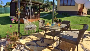 An outdoor seating area with wicker furniture, a hanging chair, and a table set for breakfast. - Artemis - Markovac Višnjan, cozy apartment with large garden and hot tub (Višnjan)