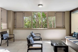 A room with a large window, a sofa, a chair, and a table.