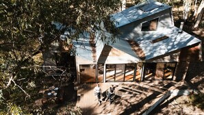 A modern house with a sloped roof, large windows, and a deck area.