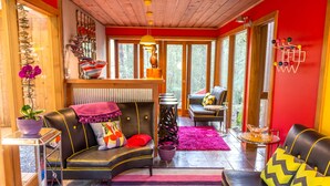 Una sala de estar acogedora con un sofá negro, un tapete rojo y una mesa de centro de vidrio.