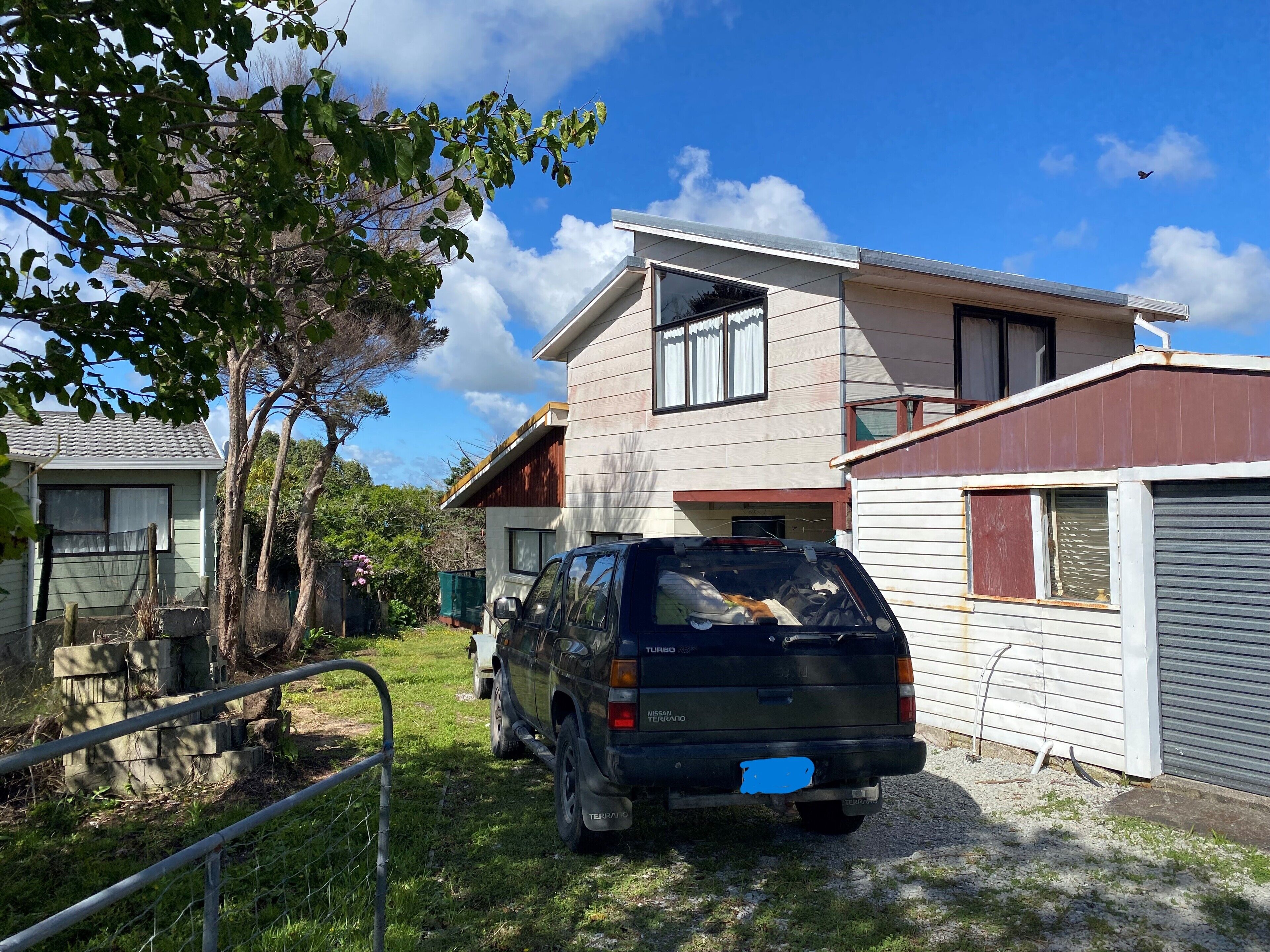 Un quartier résidentiel avec une maison, un VUS garé et une cour clôturée.