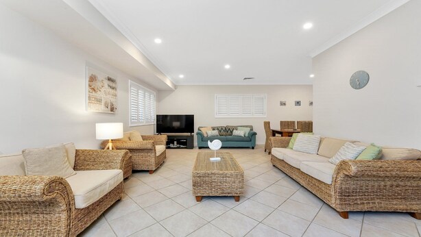 A living room with wicker furniture, a flat-screen TV, and a dining area with wicker chairs.