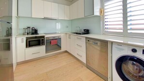 Eine moderne Küche mit weißen Schränken, einer Mikrowelle, einem Backofen und einer Waschmaschine.