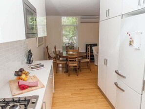 A compact kitchen with white cabinets, a dining table with chairs, a gas stove, and a refrigerator.
