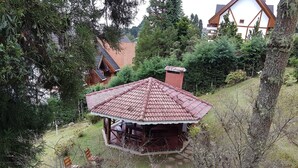 Een tuinhuis met pannendak, omringd door bomen en gazon.