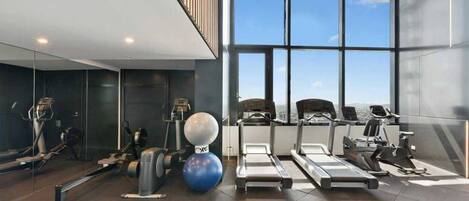 A modern gym with treadmills, elliptical machines, and a large exercise ball.
