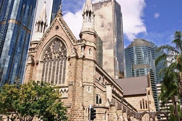 A historic building with Gothic architecture, surrounded by modern skyscrapers.
