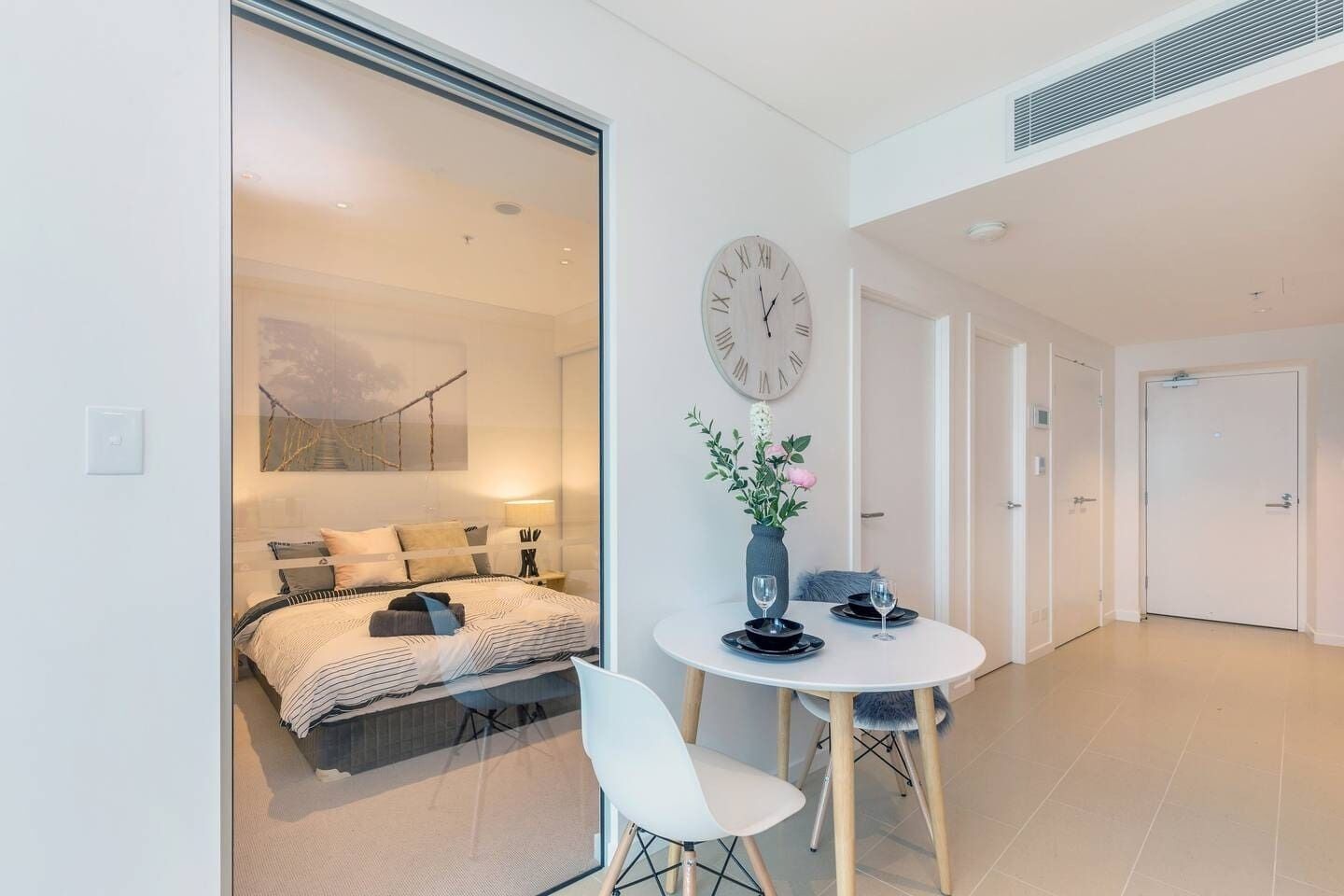 Un dormitorio moderno con cama, mesita de noche y un reloj de pared grande.