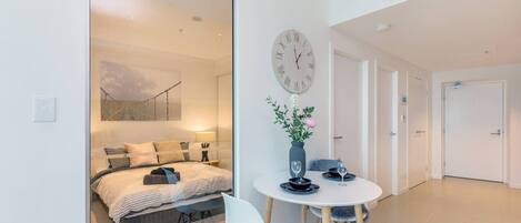 Un dormitorio moderno con cama, mesita de noche y un reloj de pared grande.