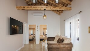 Een ruime woonkamer met een bruine bank, een witte salontafel en een aan de muur bevestigde televisie.