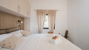 Een slaapkamer met een bed, een houten hoofdbord, een raam met gordijnen en een nachtkastje met een lamp.