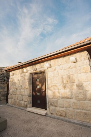 A stone building with a tiled roof, a door with a window, and a stone wall.