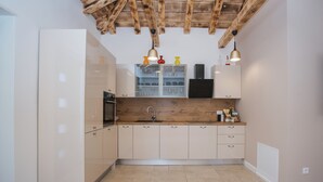 Een moderne keuken met witte kastjes, een houten aanrechtblad en een inbouwoven.