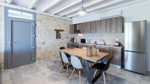 A modern kitchen with stone walls, wooden cabinets, and a stainless steel refrigerator. - Villa Thetis with private pool and sea view (Paros)