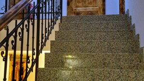 Eine Treppe mit einer Holztür oben, einem Metallgeländer und einer Leuchte darüber.