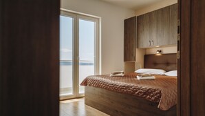 Un dormitorio con una cama de madera, una mesita de noche y un ventanal grande.