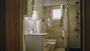 Un baño moderno con cabina de ducha de vidrio, un lavabo blanco y un inodoro.