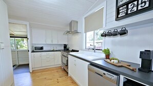 Een moderne keuken met witte kasten, een roestvrijstalen vaatwasser en een koffieapparaat.
