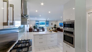 A modern kitchen with a central island, stainless steel appliances, and a view to the outside.