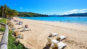 A beach with lounge chairs and a clear blue sky.