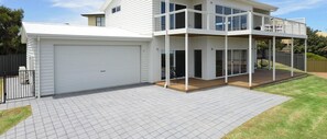 Une maison à deux étages avec un patio couvert, un garage et une cour clôturée.