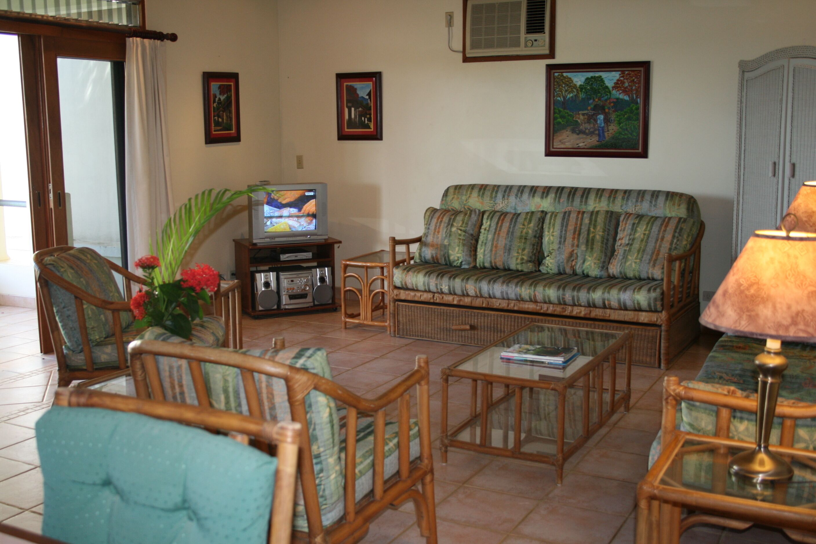 A living room with a sofa, chairs, a coffee table, a TV, and a lamp.