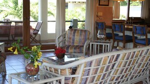 A wicker sofa with patterned cushions, a glass coffee table, and a vase with yellow flowers. - Stunning Villas, Ocean Views Plus a Pool - VILLAS CASA LOMA - Villa 2 (Playa Flamingo)