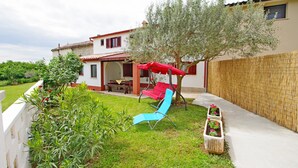 A house with a patio, a red umbrella, a blue chair, and a tree. - Holiday apartment in village Dobrani (Dobrani)