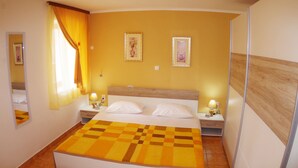 A hotel room with a large bed, two bedside tables with lamps, a checkered throw blanket, and two framed pictures on the wall. - Holiday apartment in village Dobrani (Dobrani)