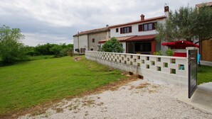 A two-story house with a stone facade, a red-tiled roof, and a gravel driveway. - Holiday apartment in village Dobrani (Dobrani)