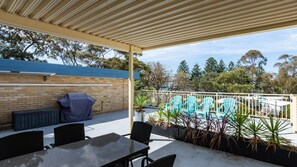 Relax in the covered patio area with a table and four chairs, perfect for al fresco dining and enjoying the pool view.