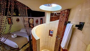Ein Badezimmer mit einer Duschwanne, einem runden Mosaikfliesenmuster, einem Handtuchhalter und einem Himmelbett.