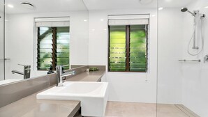Een moderne badkamer met een grote spiegel, een wastafel en een douche.