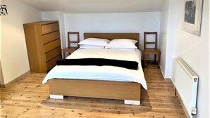 Ein Schlafzimmer mit einem hölzernen Bett, einem Schminktisch und einem Sessel.