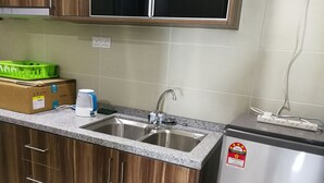 Une cuisine dotée de plans de travail en granit, d’un évier en acier inoxydable, de meubles en bois, d’une machine à café, d’une boîte et d’un petit réfrigérateur.