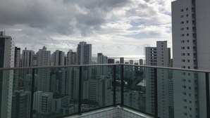 A high-rise building with a glass balcony overlooking a cityscape. - studio golden breeze 1101 (recife)