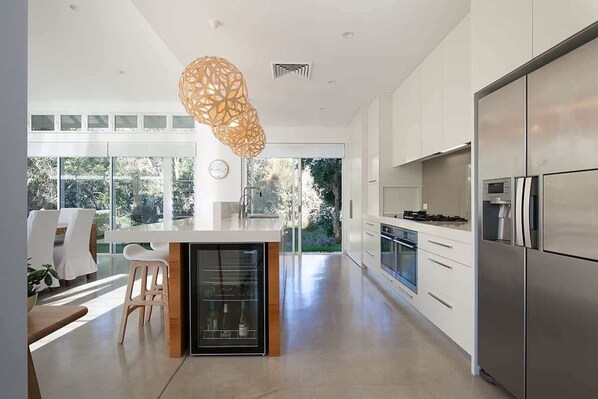 Una cocina moderna con una isla grande, electrodomésticos de acero inoxidable y vistas al exterior.