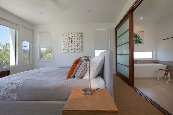 A modern bedroom with a bed, bedside table, and a desk with a chair.