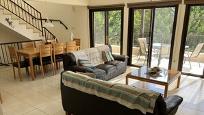 A spacious living area with a black sofa, wooden dining table, and chairs, a glass coffee table, and a staircase with a black railing. - Private Pool - All En-Suite - Games Room - Large Sun Terrace - Full A/C - WiFi (Pissouri)