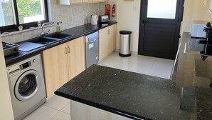 A modern kitchen with a dishwasher, washing machine, and a sink. There is a trash bin and a door with a window. - Private Pool - All En-Suite - Games Room - Large Sun Terrace - Full A/C - WiFi (Pissouri)