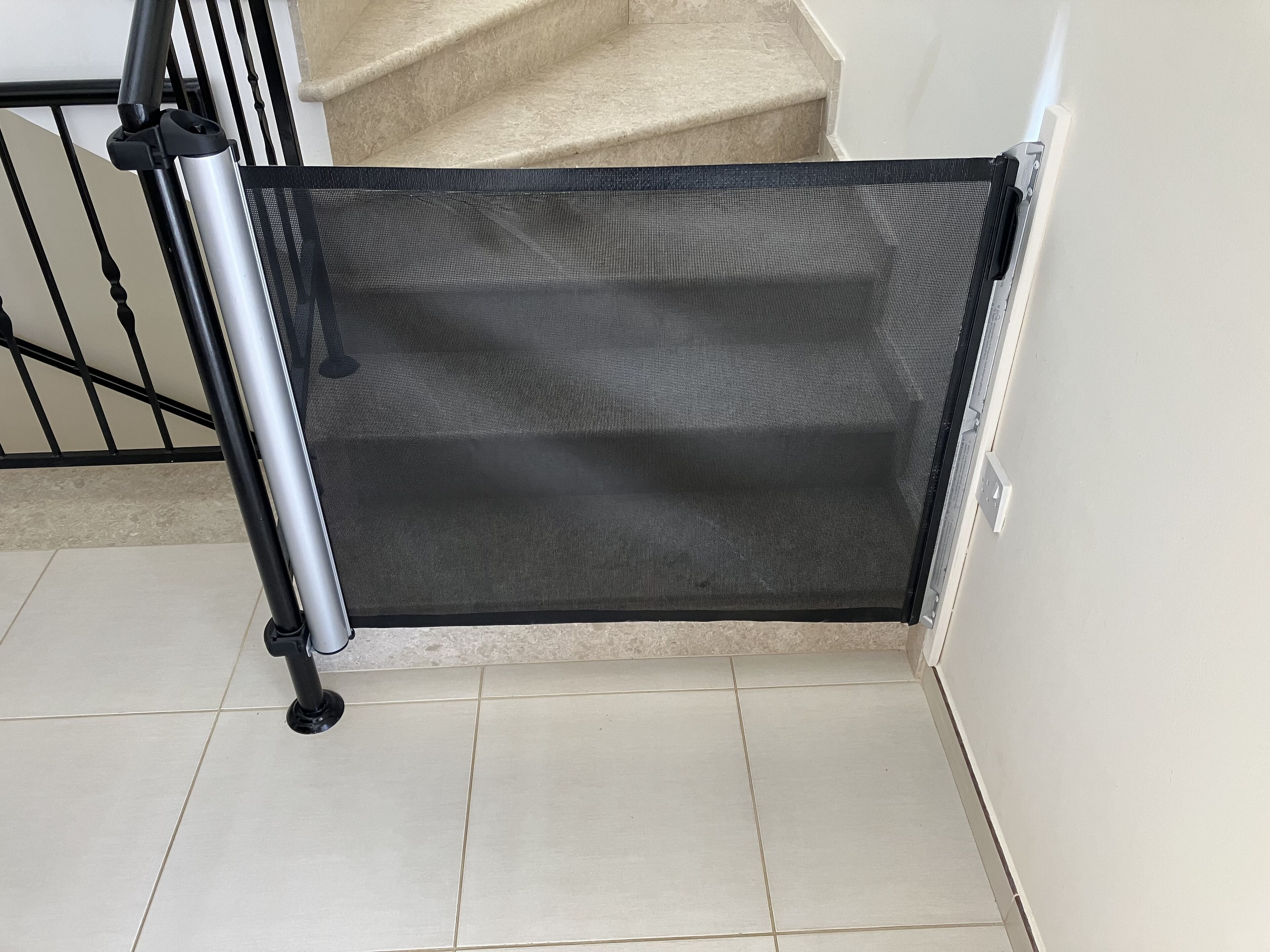 A corner of a room with a staircase, a metal railing, and a white wall.