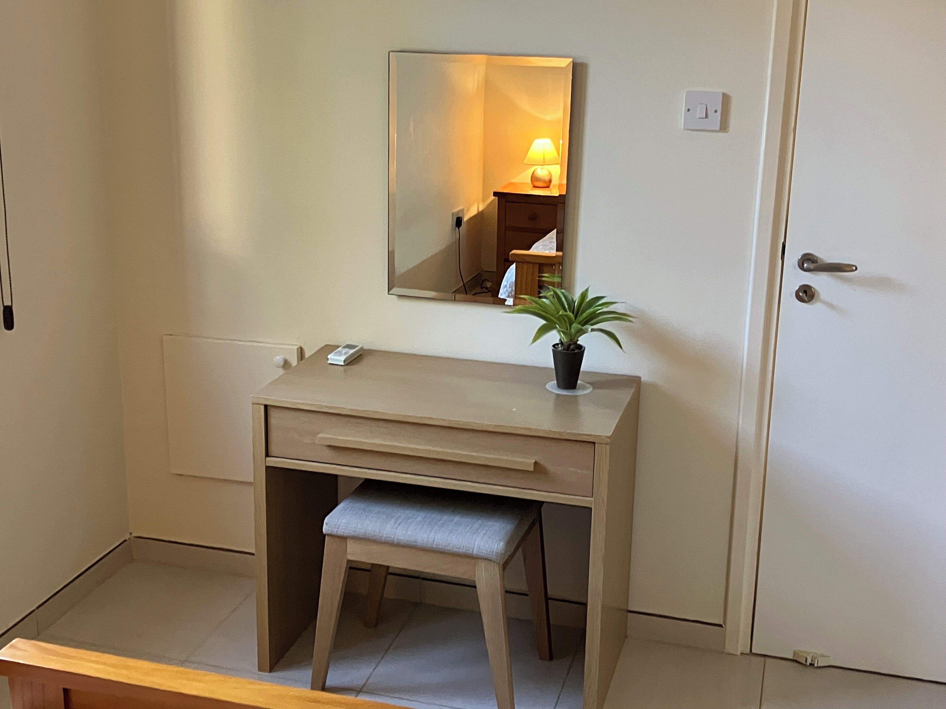 A small, neatly arranged room with a desk, chair, and a potted plant.