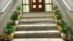 A staircase with potted plants on both sides leading to a door with glass panels.