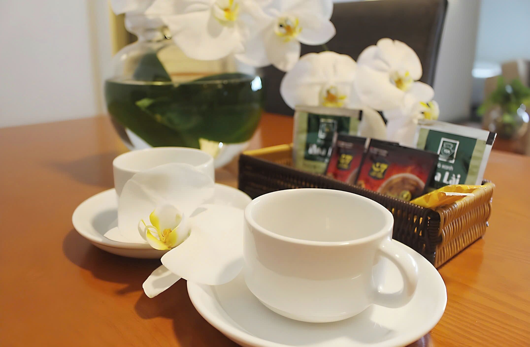 Une table avec une théière, deux tasses, une boîte de thé et des fleurs blanches.