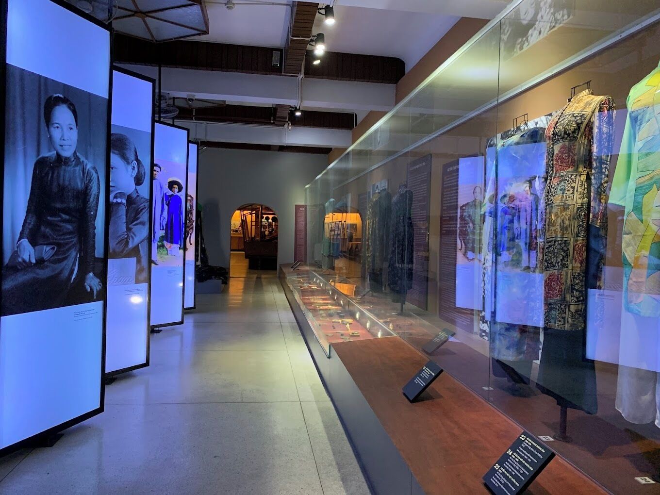 A museum exhibit with mannequins dressed in historical clothing, glass display cases, and informational plaques.