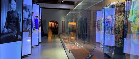 A museum exhibit with mannequins dressed in historical clothing, glass display cases, and informational plaques.