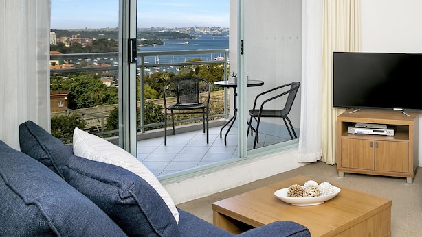 Een balkon met een televisie, een bank en een tafel met decoratieve spullen.