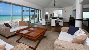 Un vaste espace de vie comprenant un grand salon avec une baie vitrée donnant sur la plage, un coin repas et une cuisine.